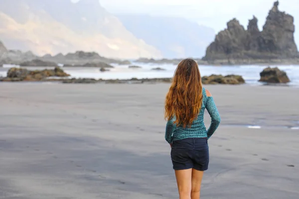 Tillbaka syn på Girl Walking reflexiv e lugn på dolda fantastiska stranden på soluppgången. Unga kvinnliga upptäcka vilda paradisön svart strand i Teneriffa. — Stockfoto