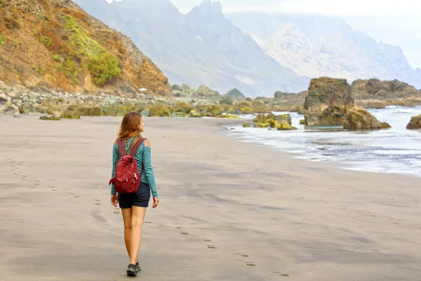 Ung kvinnlig vandrare upptäcker vilda paradisiska stranden på Teneriffa. Backview resenär flicka anländer på dolda fantastiska stranden på Kanarieöarna, Spanien. — Stockfoto