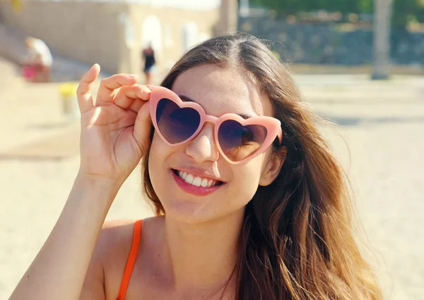 Menina sorridente no coração rosa lolita óculos de sol na praia . — Fotografia de Stock