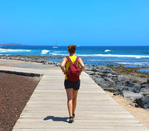 Kvinnlig vandrare gå på catwalken med spektakulära landskap av Playa de Las Americas Beach, Teneriffa, Spanien — Stockfoto