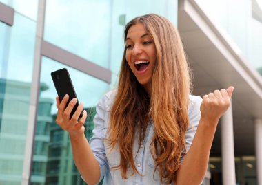 Öforik iş kadını onu akıllı telefon izlerken ve açık kazanan jest gösteren