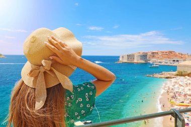 Hırvatistan'da yaz tatili. Arka planda Dubrovnik kasabası ile şapkasını tutan genç kadının arka görünümü, Hırvatistan, Avrupa.