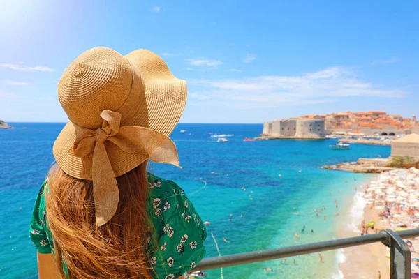 Zomer vakantie in Kroatië. Achteraanzicht van jonge vrouw met stro hoed en groene jurk met Dubrovnik oude stad op de achtergrond, Kroatië, Europa. — Stockfoto