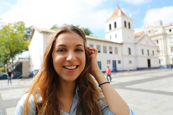 Счастливая улыбающаяся молодая женщина в центре города Сан-Паулу с достопримечательностью Патио-ду-Коледжио на заднем плане, Сан-Паулу, Бразилия — стоковое фото