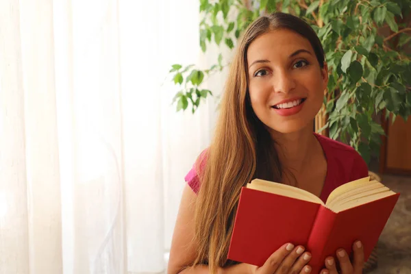 Lindo livro de leitura menina em casa olhando câmera. Espaço de cópia . — Fotografia de Stock