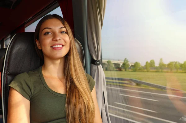 Usmívající se dívka, která cestuje autobusem s cestou z okna a dívá se na kameru — Stock fotografie