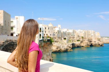 Apulia'da yaz tatili. Polignano Akdeniz'de bir mare kasabasında güzel genç kadının arka görünümü, İtalya.