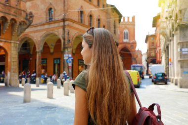 İtalya'nın Bologna kentinin eski ortaçağ kasabasında yürüyen çekici genç kadının arka görünümü.