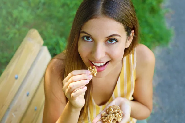 Vista de perto de cima de uma mulher comendo nozes ao ar livre. Conceito de alimentação saudável . — Fotografia de Stock