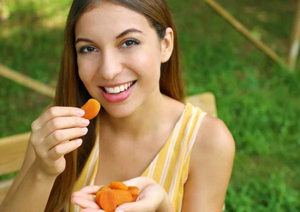 Une jeune femme qui mange des fruits secs dans le parc. Concept d'alimentation saine . — Photo