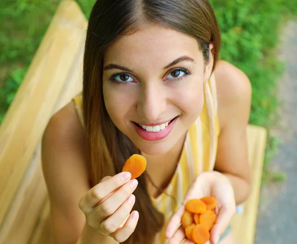 Fiatal nő eszik szárított sárgabarack a parkban. Egészséges táplálkozás koncepció. — Stock Fotó