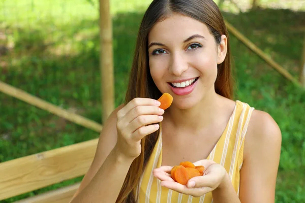 Jonge vrouw die gedroogde vruchten in het Park eet. Gezond voedsel concept. — Stockfoto