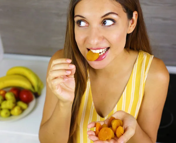 Mujer joven comiendo albaricoques secos en casa. De cerca desde arriba mirando hacia un lado. Concepto saludable . —  Fotos de Stock