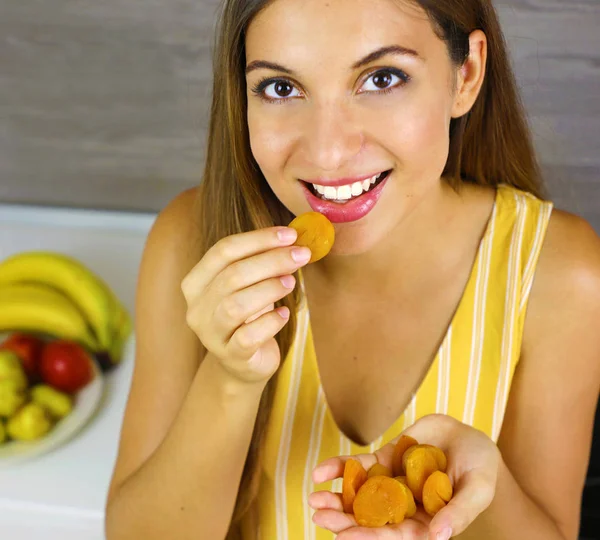 Красивая веселая молодая женщина ест вкусные обезвоженные абрикосы дома. Закрыть сверху. Здоровое понятие . — стоковое фото