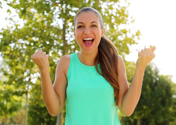 Winning, success concept. Beautiful, fitness sporty girl rejoices in victory, raises her fists in a sign of victory. Positive emotions and feelings.