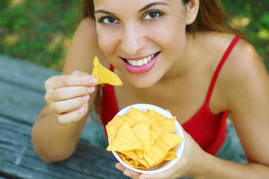 Açık havada tortilla cipsi yiyen güzel genç kadının yukarıdan yakından görünümü.