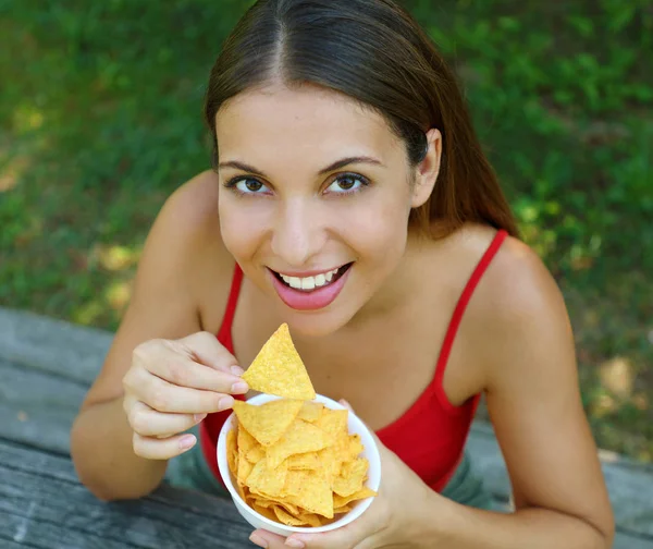 Close-up vista de cima de bela jovem mulher comendo chips de tortilla ao ar livre . — Fotografia de Stock