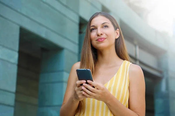 Hermosa mujer de negocios determinada mensajes de texto fuera de la oficina con el teléfono inteligente . —  Fotos de Stock