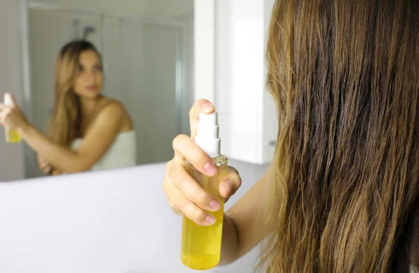 Жінка наносить масляну маску на волосся перед дзеркалом. Концепція догляду за волоссям. Фокус на волоссі . — стокове фото