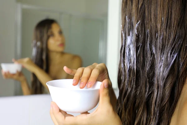 Hair masking. Young woman hand applying natural mask on long healthy hair. Health and beauty concept. — Stock Photo, Image