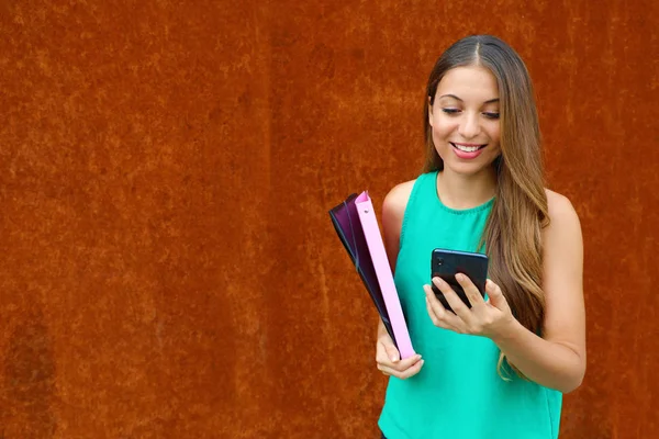 Jovem mulher de negócios digitando no telefone inteligente com fundo ferrugem e espaço de cópia . — Fotografia de Stock