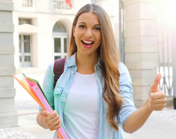 Happy student girl doing student exchange programme in Europe. Young woman gives thumb up outdoor. — Stock Photo, Image