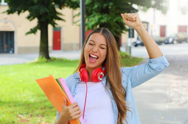 Portrait of an excited teenager girl raising arm and laughing outdoors in the street. — Stock Photo, Image
