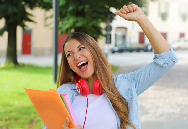 Portrait of an excited teenager girl raising arm and laughing outdoors in the street. — Stock Photo, Image