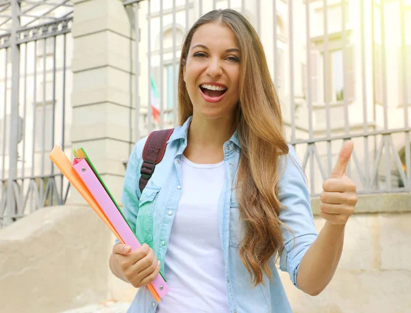 Happy student girl doing student exchange programme in Europe. Young woman gives thumb up outdoor. — Stock Photo, Image
