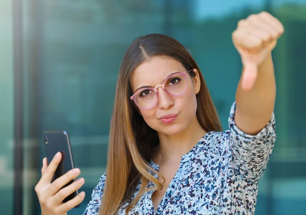 Mujer de negocios joven molesto da pulgar hacia abajo después de ver su nueva aplicación de teléfono inteligente . —  Fotos de Stock