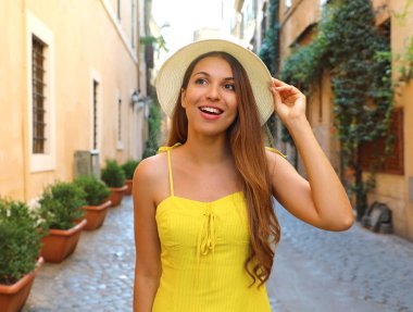 Trastevere mahalle Roma, İtalya yürüyüş sarı yaz elbise şapka ve uzun saçlı güzel moda kadın zarif portre.
