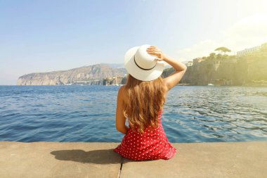 Sorrentine Yarımadası'nda Sorrento köyünün çarpıcı panoramik bakarak kenarında oturan şapkaile güzel genç kadın, İtalya.