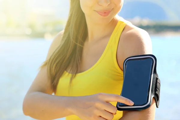 Opaska sportowa na smartfon. Sportowa kobieta dotykając jej inteligentnego telefonu przed treningiem fitness na zewnątrz na plaży. — Zdjęcie stockowe