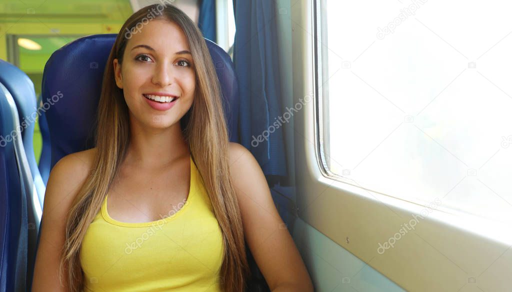Young attractive woman in yellow tank top sitting in the train smile at camera.