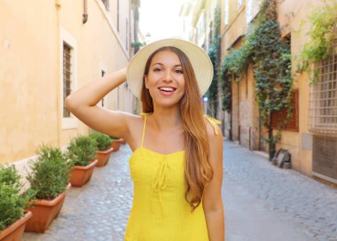 Trastevere, Roma 'da güzel bir kız. Sarı elbiseli ve şapkalı güzel moda kadını Roma, İtalya sokaklarında yürüyor..