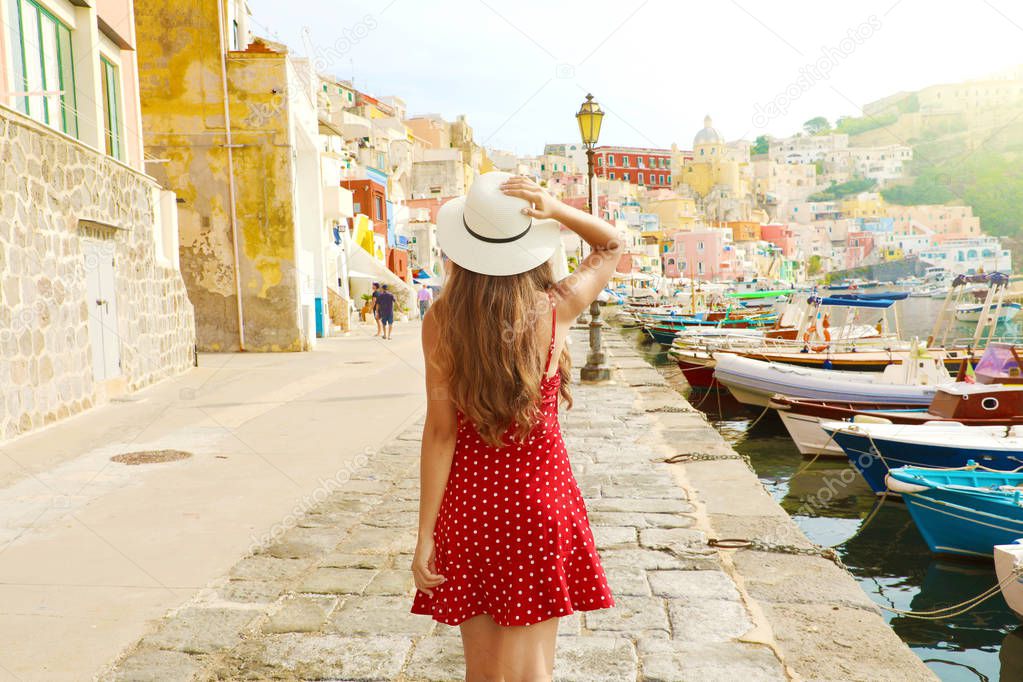 Holidays in Italy. Back view of beautiful girl in stunning colorful harbor of Procida in Italy.