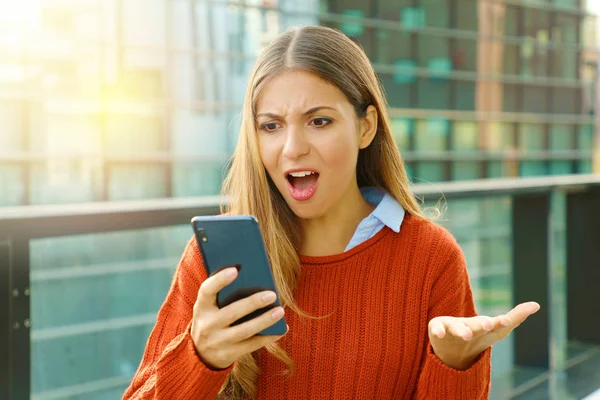 Disappointed angry woman receiving wrong content online on mobile phone walking in the street. — Stock Photo, Image