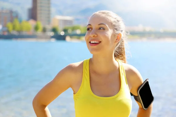 Szczęśliwy fitness kobieta noszenie aktywnego odzieży i sportu opaska smartfon puste do reklamy do biegania lub treningu cardio na plaży. — Zdjęcie stockowe