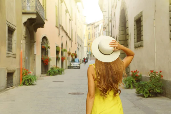 Bagside visning af turist kvinde gå og holde hat på Via Pignolo gade i Bergamo gamle bydel, Italien . - Stock-foto