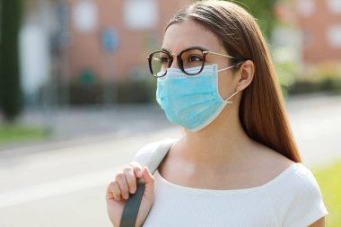Şehirde SARS-CoV-2 virüsü yaymak için koruyucu maske takan genç bir kadın. Coronavirus Hastalığı 2019 'a karşı cerrahi maskeli bir kız..
