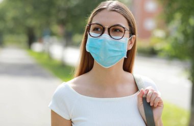 Şehirde SARS-CoV-2 virüsü yaymak için koruyucu maske takan genç bir kadın. Coronavirus Hastalığı 2019 'a karşı cerrahi maskeli bir kız..
