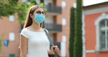 Portrait of young woman walking in city street wearing protective mask clipart