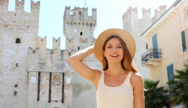 Arka planda Sirmione Kalesi olan gülümseyen turist kadın portresi, Garda Gölü, İtalya