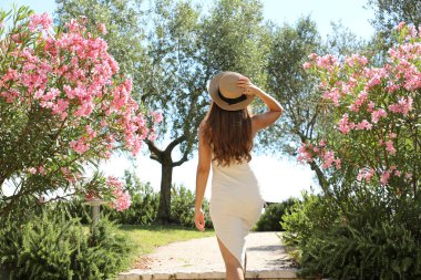 Güzel seksi moda kadını Sirmione 'de Garda Gölü, İtalya' da çiçekler arasında bir bahçeye girer.