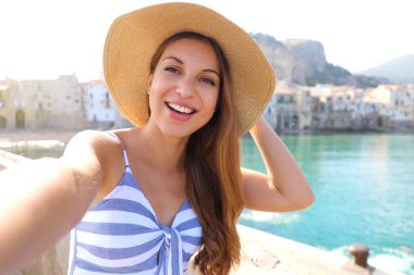 Gülümseyen kadın yaz tatilinde Cefalu, Akdeniz, İtalya 'da selfie çekiyor.