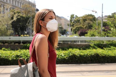 Şehir caddesinde KN95 FFP2 maskeli 19 kadın SARS-CoV-2 virüsünün yayılmasını önlüyor. Coronavirus Hastalığı 2019 'a karşı koruyucu maskeli bir kız..