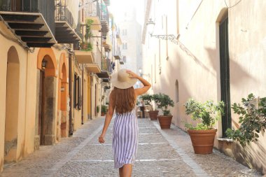 İtalya 'nın Sicilya kentindeki eski Cefalu kasabasında yürüyen turist kadının arka manzarası
