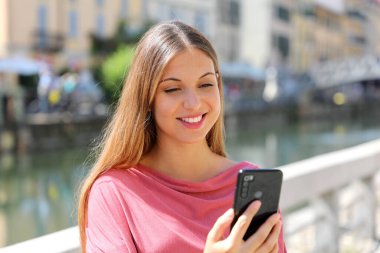 Şehrin sokaklarında akıllı telefon uygulaması ile gülümseyen genç kadın videolarını kapatın.