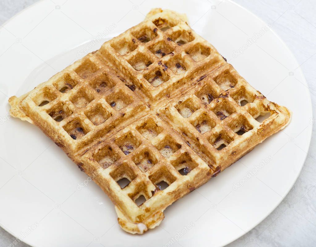 Homemade square belgian waffle on white plate