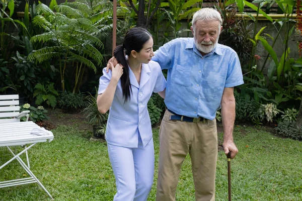 Hombre mayor felicidad y enfermera sonriente, cuida y discute — Foto de Stock